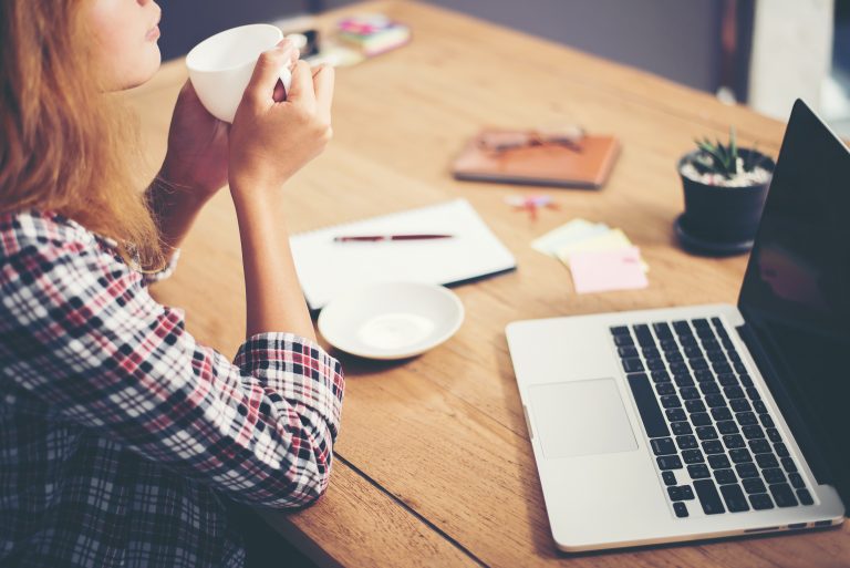 Young business woman sitting in office desk with cup of coffee r